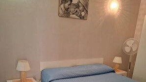 A bedroom with a bed, bedside tables, a lamp, and a wall-mounted artwork.