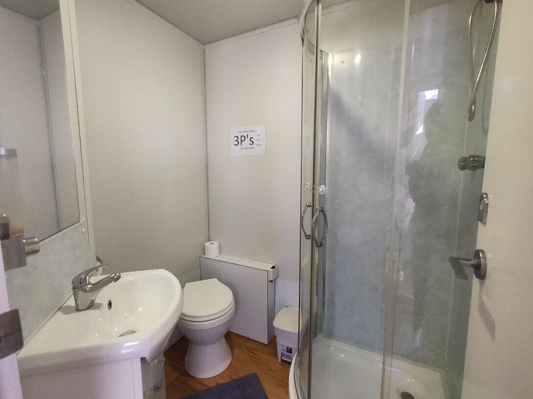 Un baño pequeño con lavamanos, inodoro y ducha con mampara de vidrio.