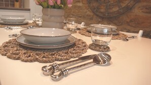 A table set with plates, bowls, cutlery, and a vase of flowers. - Immaculate 1-bed Cottage in Moreton in Marsh (Moreton-in-Marsh)