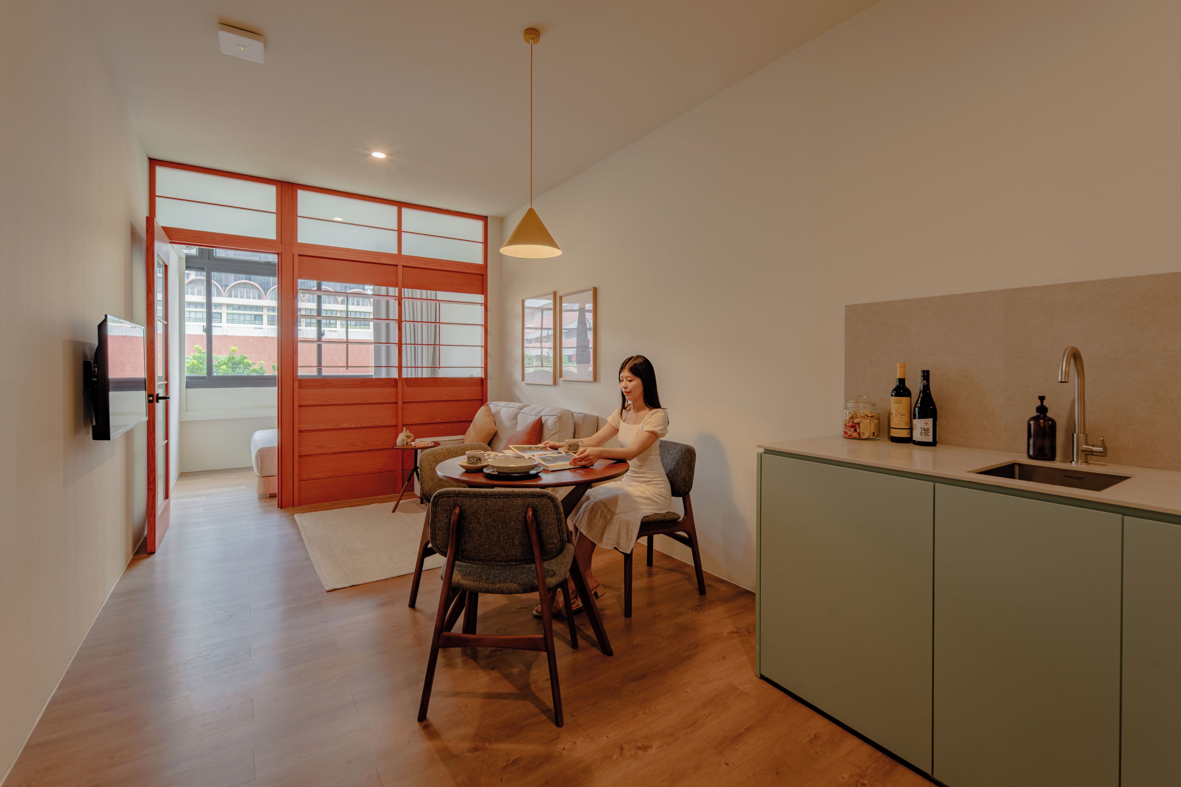 A modern kitchen with a dining area, wooden flooring, and a large window.