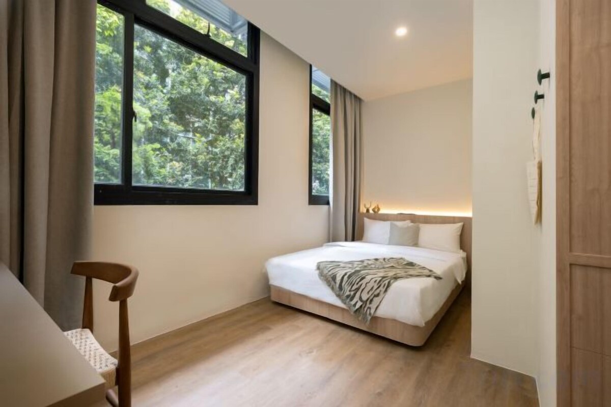 A bedroom with a bed, a chair, and a window.
