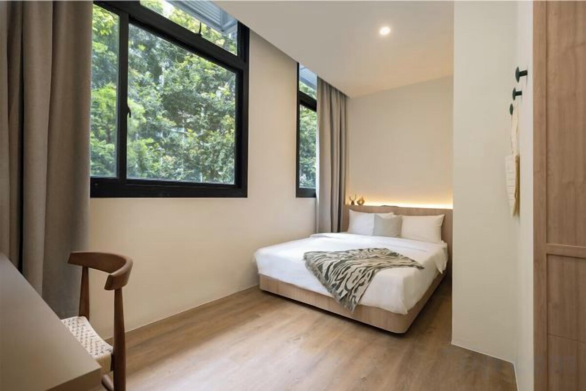 A bedroom with a bed, a chair, a window, and a door.