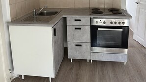Una cocina compacta con lavamanos, estufa y cajones para guardar objetos.