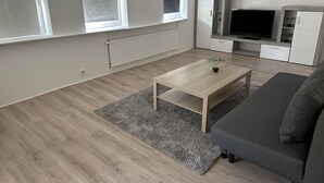 Una sala de estar moderna con sofá, mesa de centro y televisión.