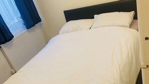 A neatly made bed with white linens in a hotel room. - Beautiful portable single room in an apartment  (Bury)