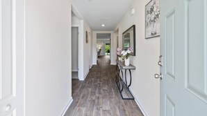 Un pasillo con suelo de madera, paredes blancas y una puerta con detalles azul claro.