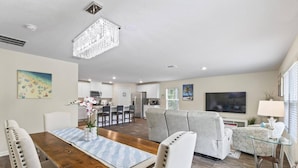 Una sala de estar moderna con comedor, cocina y televisor.