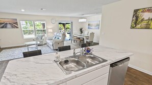 Una cocina moderna con encimera de mármol, pileta de acero inoxidable y lavavajillas.