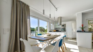 A modern kitchen with white cabinets, a central island, and a dining area with a table and chairs. - Villa for rent in Benissa, AZUR. (Benissa)
