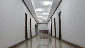Um corredor comprido e estreito, com paredes brancas e chão de azulejos brilhantes.