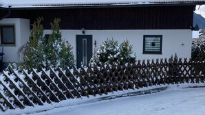 Un edificio cubierto de nieve con una valla de madera y árboles nevados.