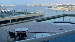 Une terrasse sur le toit avec une piscine, des garde-corps en verre et une vue sur le paysage urbain.