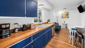 A modern kitchen with blue cabinets, a wooden countertop, a coffee maker, a toaster, and a sink. - Beautiful and cozy apartment in Bonita w/Garden  (Bonita Springs)