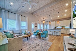 A spacious living area with a sofa, chairs, a coffee table, and a kitchen in the background.