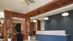 Un área de recepción con un mostrador de madera, un espejo grande y una lámpara de araña moderna.