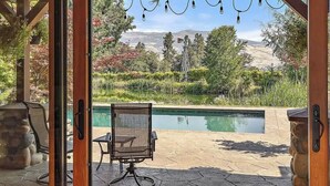 Um pátio externo com piscina, uma cadeira e vista para uma paisagem montanhosa.