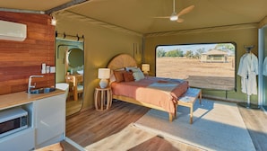 Une chambre spacieuse comprenant un lit, des tables de chevet, un petit bureau et une vue sur l’extérieur.