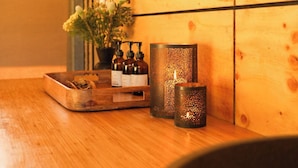 Une table en bois avec un plateau, des bougies et une plante en pot.