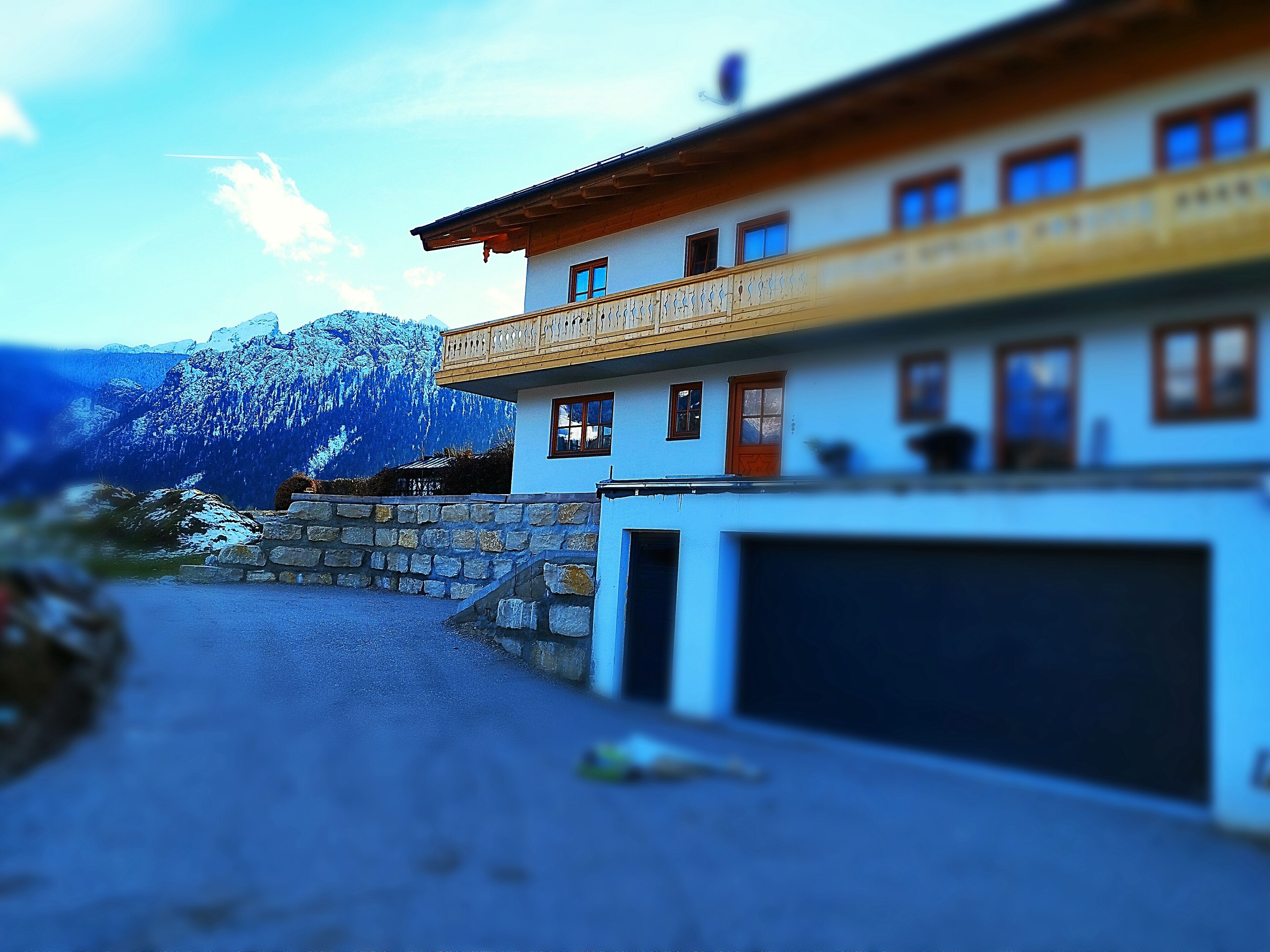 Ein zweistöckiges Gebäude mit Garage, Mauerwerk und Blick auf einen Berg.