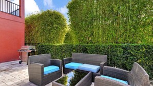 A patio area with wicker furniture and a grill. - Disney-Area Home w/ Themed & Media Room, Pool Table & Waterpark - 240CL (Kissimmee)