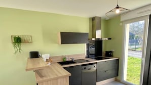 Een moderne keuken met een houten aanrecht, zwarte kastjes en een ingebouwde vaatwasser.