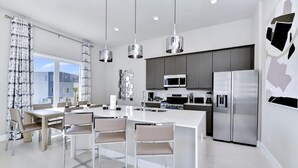 A modern kitchen with stainless steel appliances, a central island with seating, and pendant lighting.