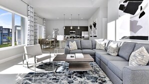 A modern living room with a grey sectional sofa, a coffee table, and a patterned rug.