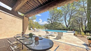 An outdoor patio with a table set for dining, surrounded by chairs, and overlooking a swimming pool. - Villa San Michele - 70's Experience (Salernes)