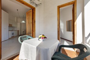 A small dining area with a table set for two, a fruit bowl on the table, and a view of the kitchen in the background. - 3736 Appartamento Fiorita by Barbarhouse (Vernole)