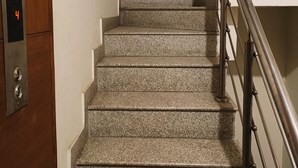 Eine Treppe mit Granitstufen, einem Metallgeländer und einer Holztür mit einem Aufzugstaster mit der Nummer 4.
