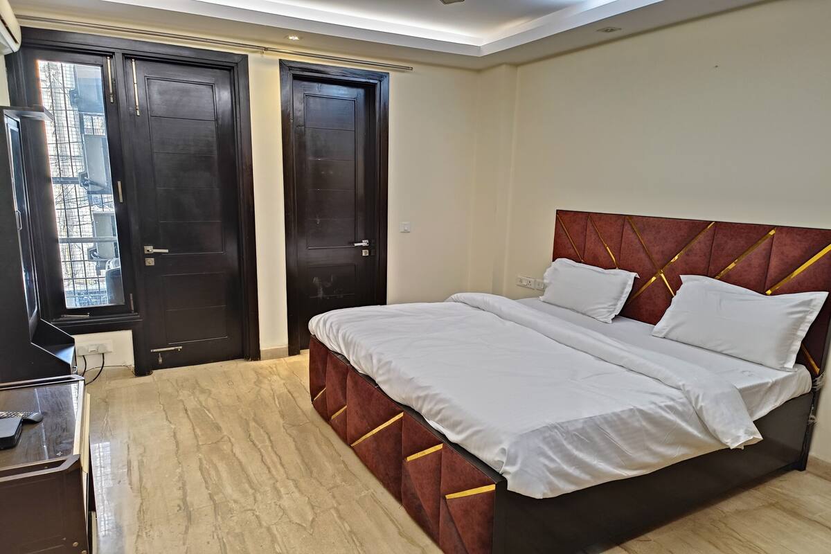Ein Schlafzimmer mit einem großen Bett, einem Schreibtisch und zwei dunklen Holztüren.