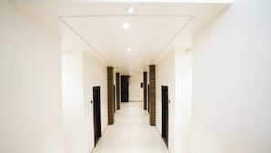 A long, narrow hallway with white walls and a tiled floor, leading to a door at the end. - Madhav Residency Hotel & Banquet, Kalyan, Mumbai (Thane)