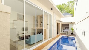 A modern house with a glass-enclosed living area, a pool, and a patio. - Rustic Pandawa Villa (Kutuh)