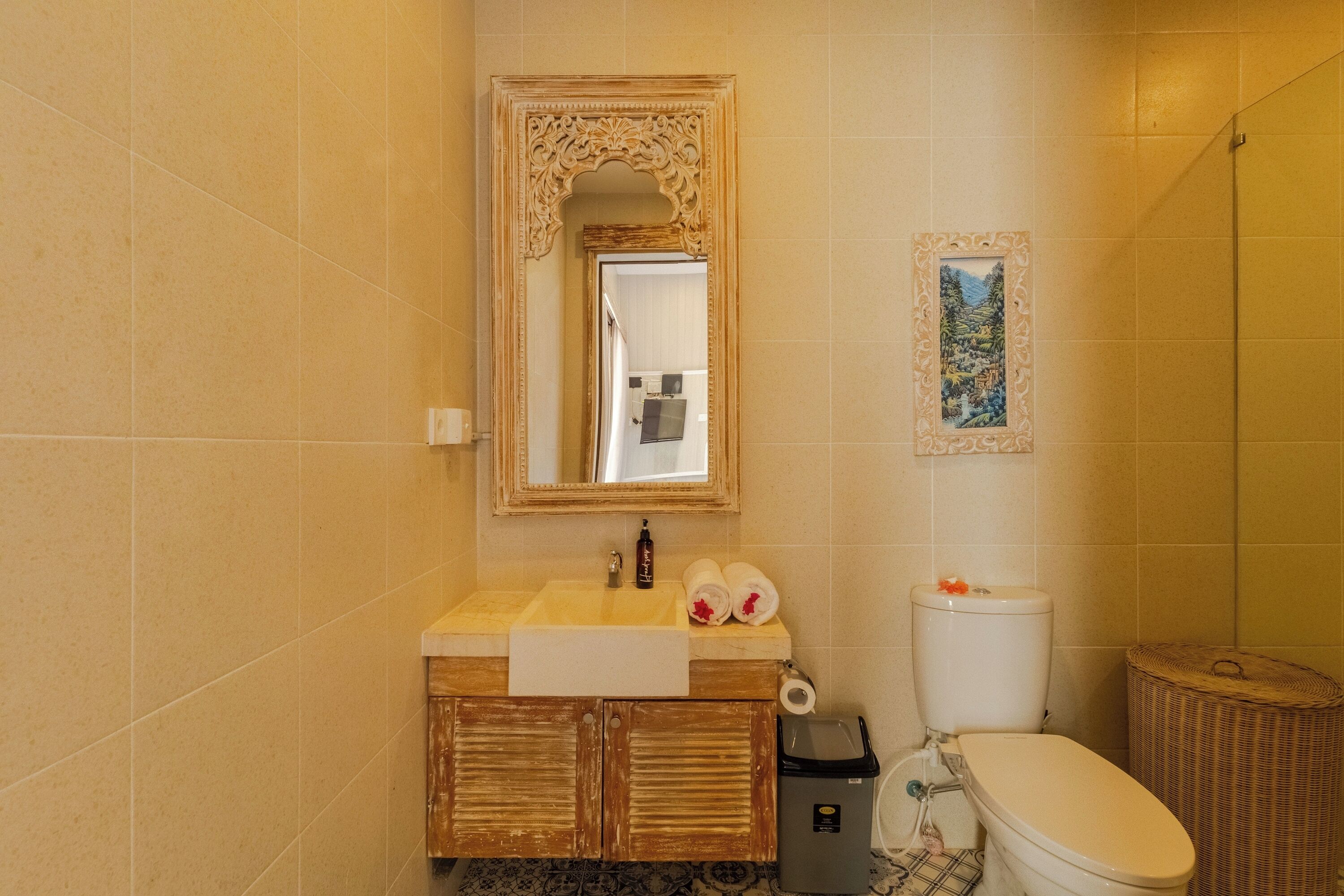 A bathroom with a sink, mirror, toilet, and a wicker basket.