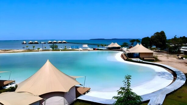 Un resort con una grande piscina, cabine da spiaggia e vista sul mare.