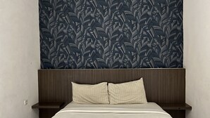 A bed with a headboard, two bedside tables, and a patterned wallpaper. - Good Day Inn (Jakarta)