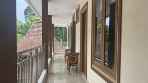 A corridor with a tiled floor, wooden chairs, and a balcony with metal railings. - Gb 2 Backpacker Borobudur (Borobudur)