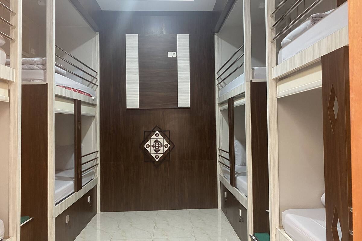 A room with bunk beds, a wooden wardrobe, and a decorative wall panel.