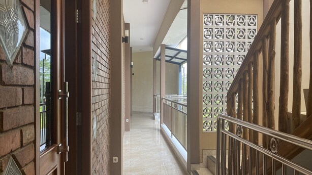 A corridor with a wooden door, brick walls, and a metal railing. - Gb 2 Backpacker Borobudur (Borobudur)