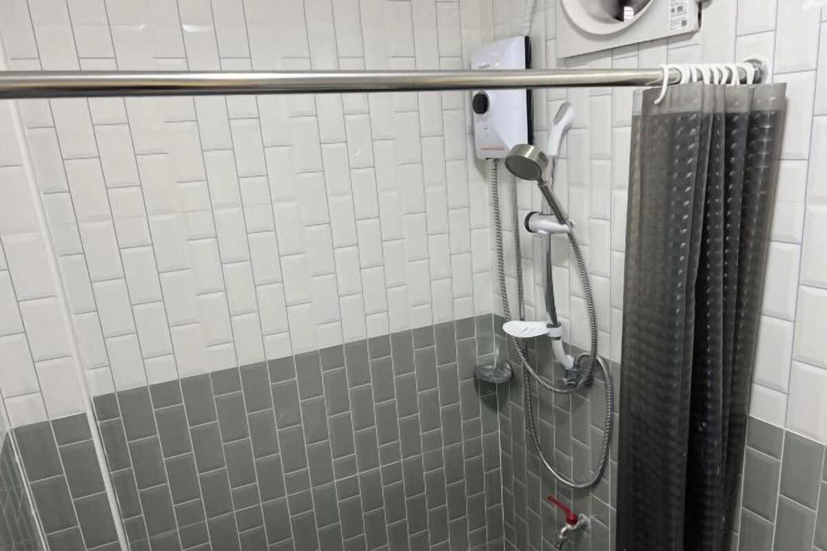 A shower area with a tiled wall, a showerhead, and a curtain.