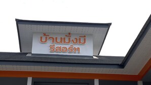 Ein Gebäude mit einem Schild, auf dem 'Thai Massage' in Englisch und einer anderen Sprache steht.