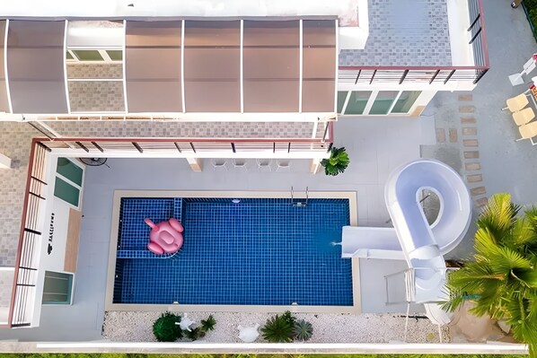 A modern building with a swimming pool, a slide, and outdoor seating.