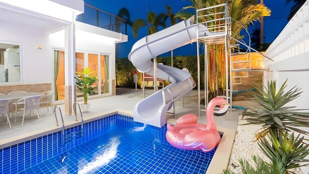 Uima-allas, jossa on liukumäki, vaaleanpunainen flamingo-uimapatja ja portaat, jotka johtavat parvekkeelle.
