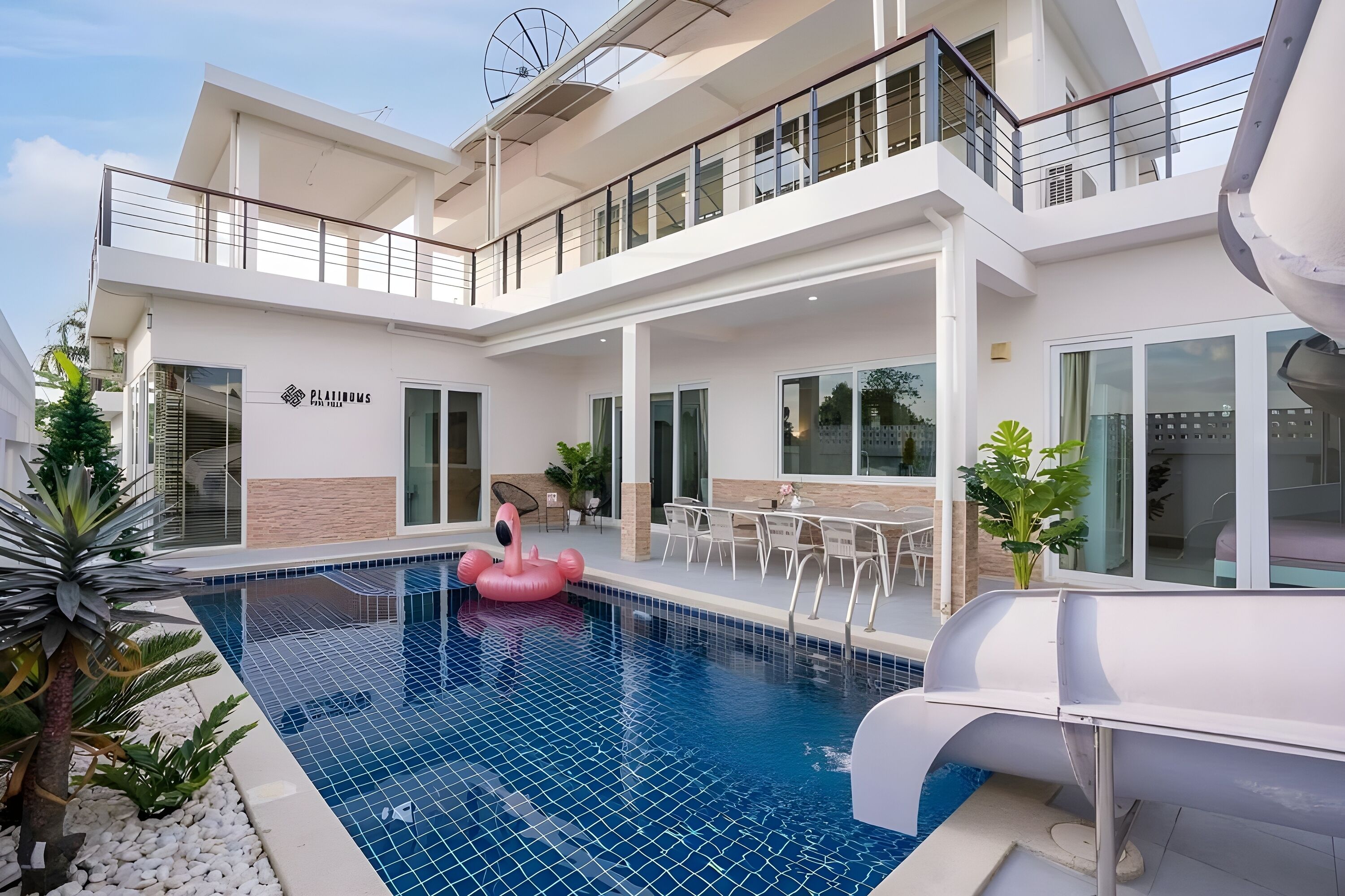 Un hotel moderno con piscina, tobogán y zona de estar exterior.
