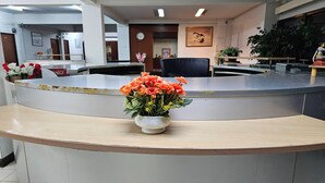 A reception desk with a vase of flowers, a clock, and a framed picture on the wall.