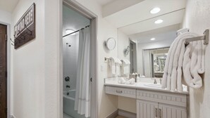 Ein Badezimmer mit einem weißen Waschtisch, einem großen Spiegel und einer Dusche mit Glastür.