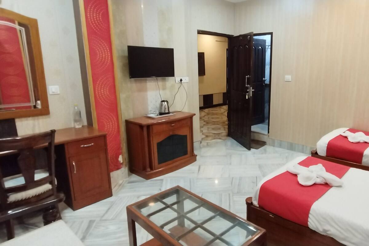 A hotel room with two beds, a desk, a chair, a TV, and a mirror.