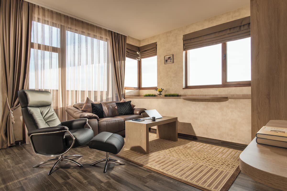 A modern living room with a leather sofa, a black office chair, a wooden coffee table, and a small side table.