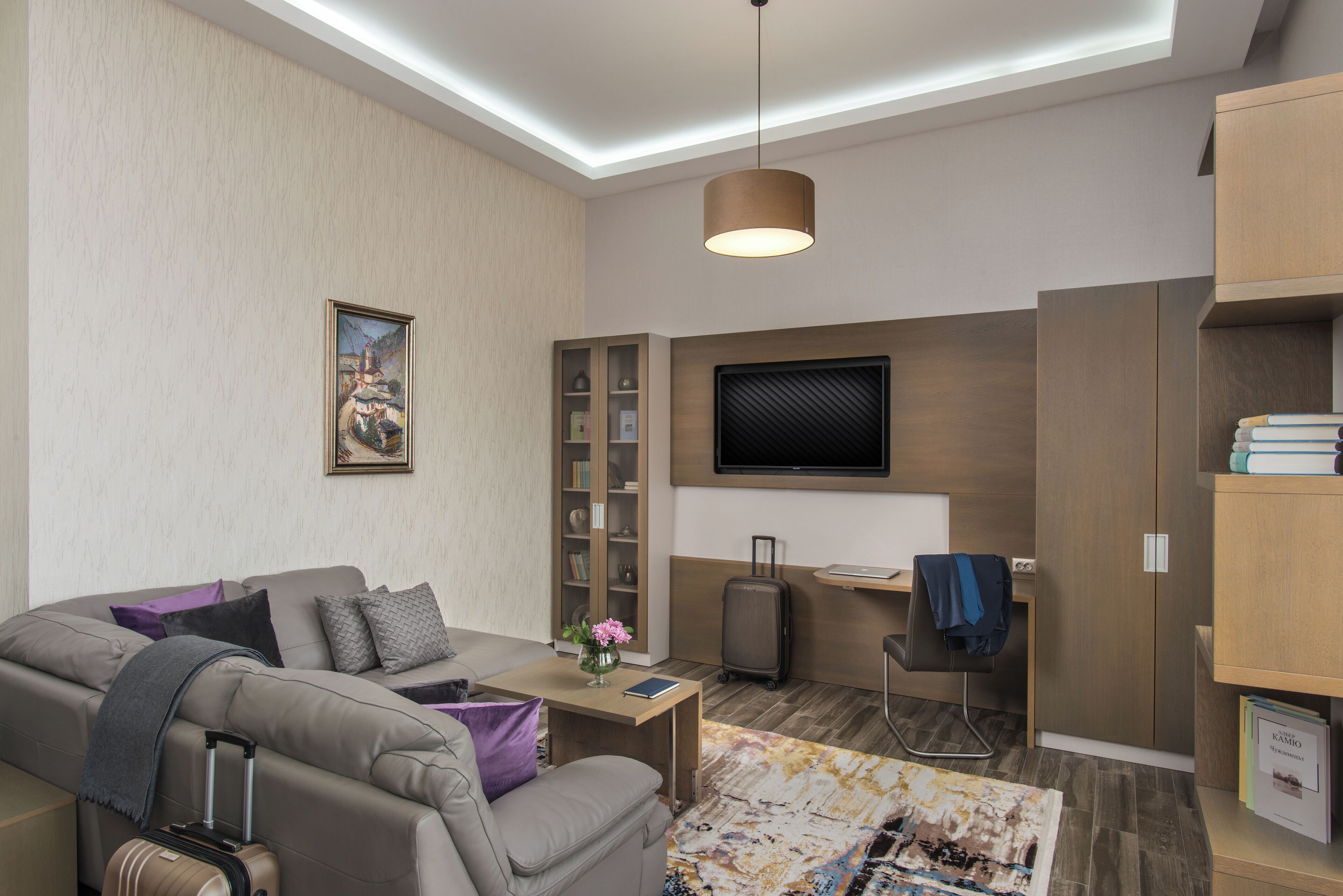 Una sala de estar moderna con un sofá, una mesita, un televisor y una estantería.