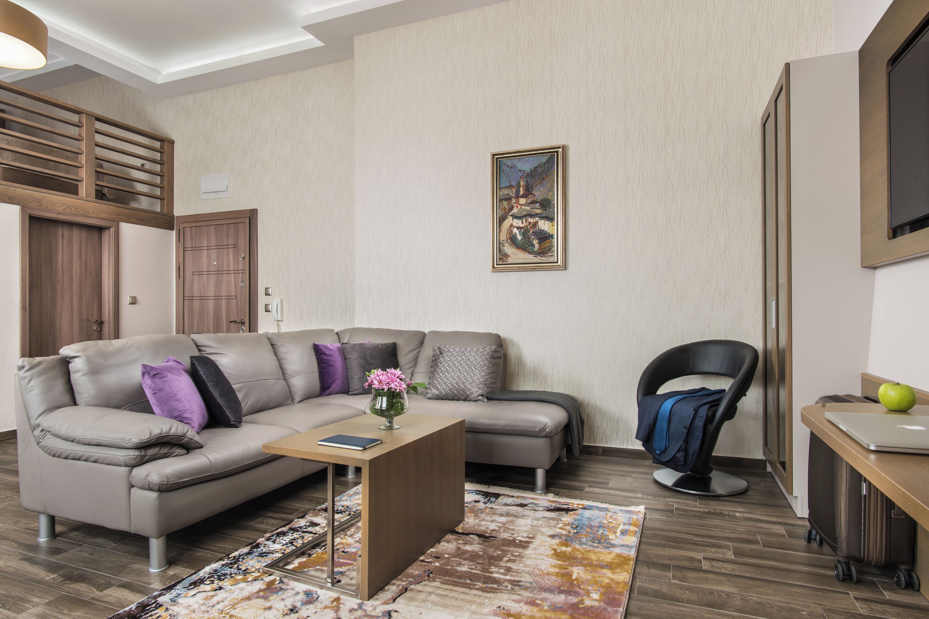 Ein modernes Wohnzimmer mit einer Eckcouch, einem kleinen Couchtisch, einem Sessel und einem Bild an der Wand.